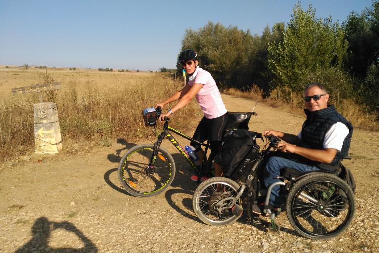 Pareja en handbike y bicicleta en el Camino de Santiago