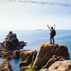 Senderista en la costa de Inglaterra, en una roca frente al mar